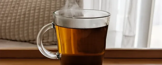 tasse avec décoction de kinkéliba posée sur une surface en bois