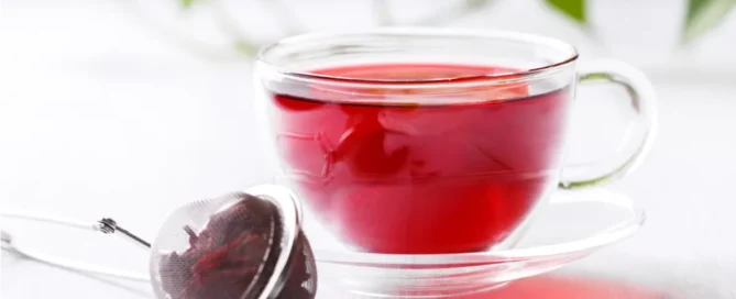 boule d'infusion de bissap pour préserver la vitamine C à côté d'une tasse transparente avec infusion d'hibiscus dedans