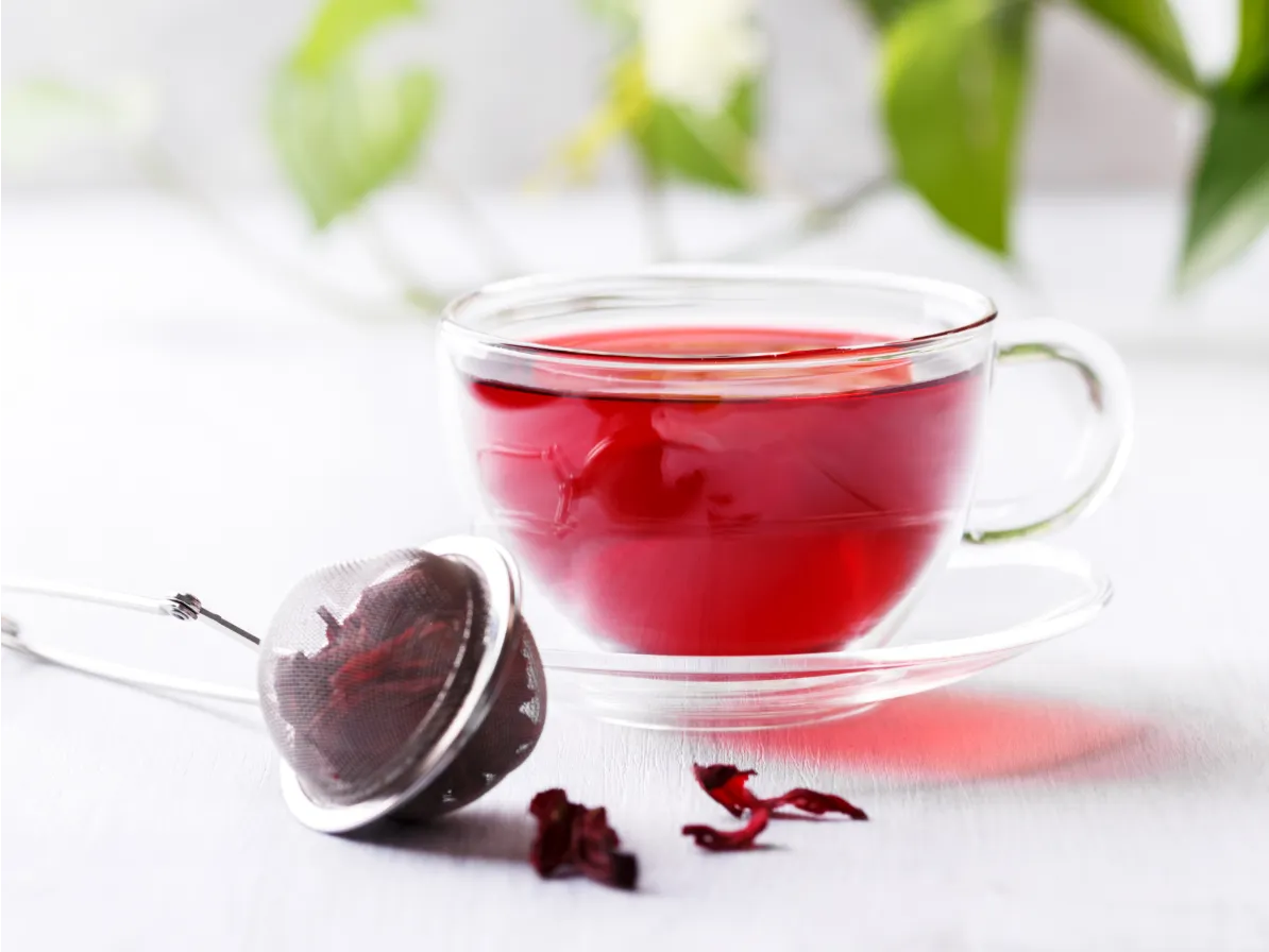 boule d'infusion de bissap pour préserver la vitamine C à côté d'une tasse transparente avec infusion d'hibiscus dedans