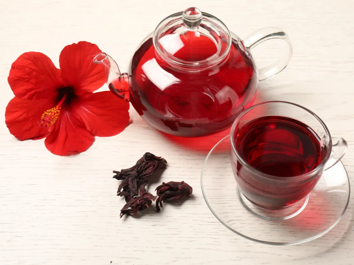 théière contenant du bissap ainsi qu'une tasse transparente avec du bissap dedans vue de haut pour parler de l'utilisation du bissap dans le cycle menstruel