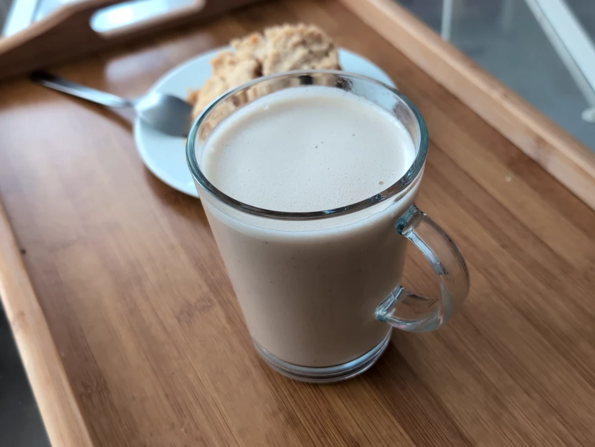Un latte au baobab posé sur un plateau en bois avec une part de crumble aux pommes derrière