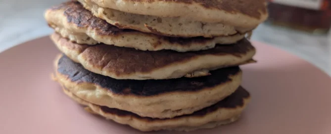 Pile de pancakes avec poudre de baobab posés dans une assiette rose