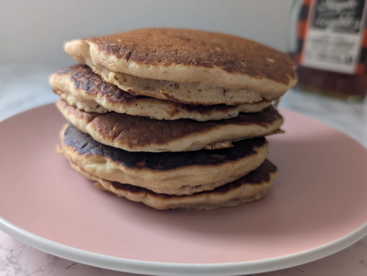Pile de pancakes avec poudre de baobab posés dans une assiette rose