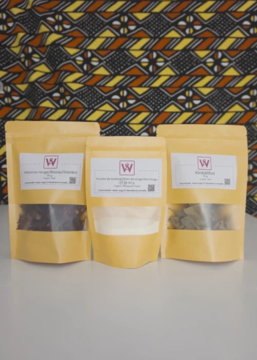 3 sachets en kraft posés sur une table blanche, chaque sachet contient de l'hibiscus de la poudre de baobab et du kinkéliba
