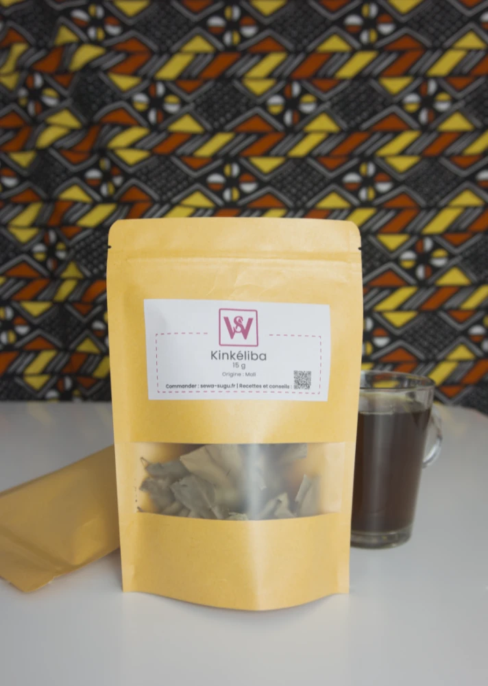 Sachet kraft de kinkéliba posé sur une table avec un verre de kinkéliba posé à droite